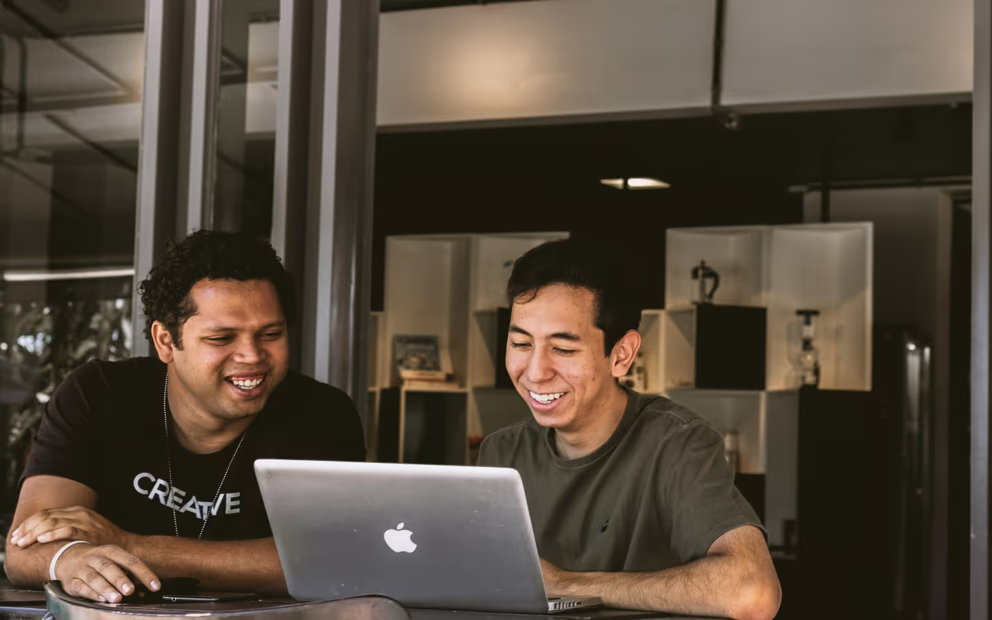 Deux programmeurs souriants regardant l'écran d'un ordinateur portable